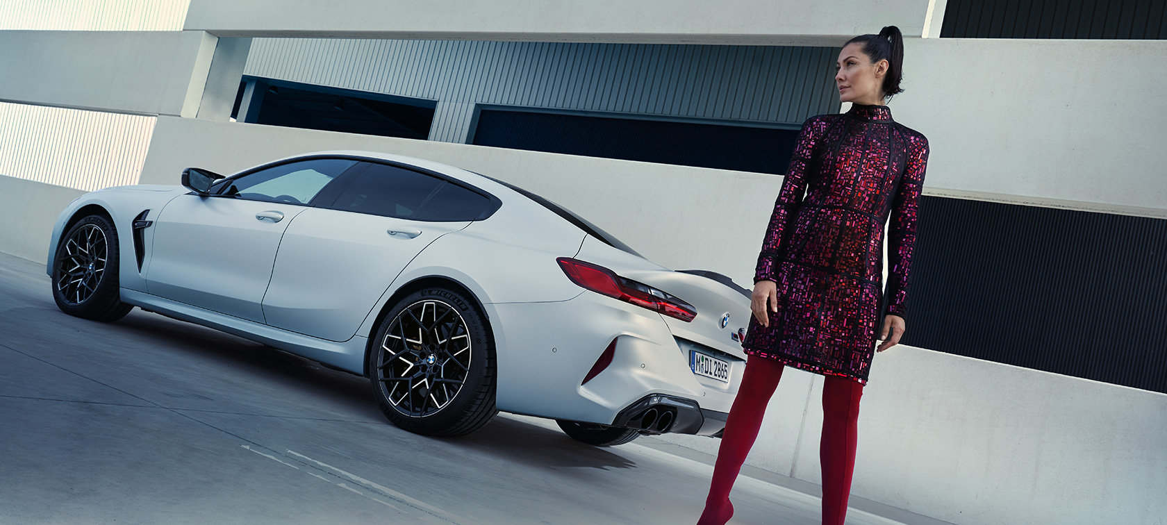 Perspetiva traseira a três quartos, o BMW M8 Competition Gran Coupé, F93, LCI, 2022 O BMW M8 Competition Gran Coupé, F93, atualização, 2022, pintura branco Frozen Brilliant BMW Individual metalizada, perspetiva traseira a três quartos com um modelo feminino parado ao lado do veículo