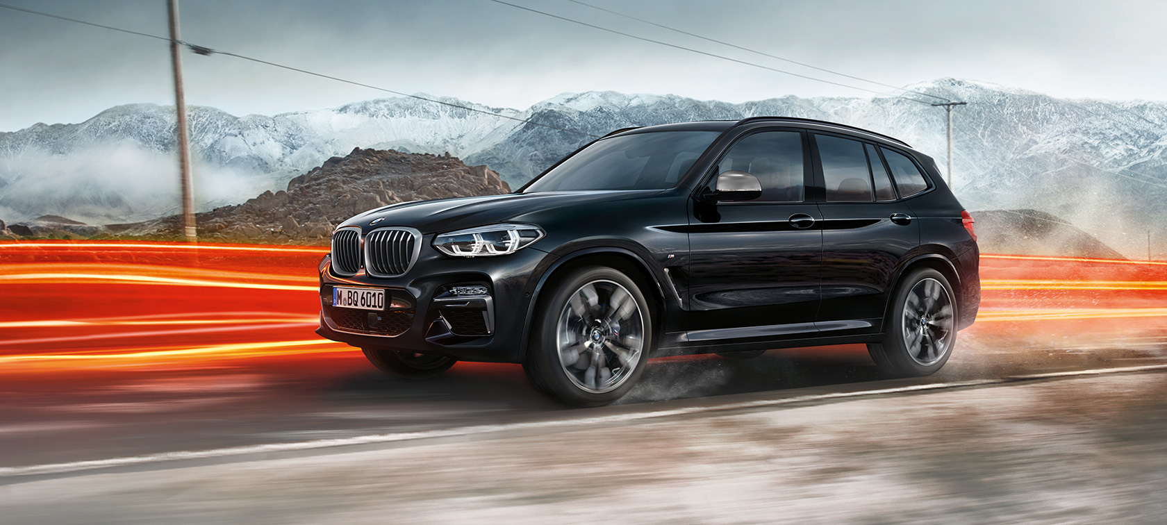 BMW X3 M40d, perspetiva lateral. BMW X3 M40d na pintura preto Sapphire metalizada em movimento, exterior, perspetiva lateral, em cenário urbano com faixas luminosas.