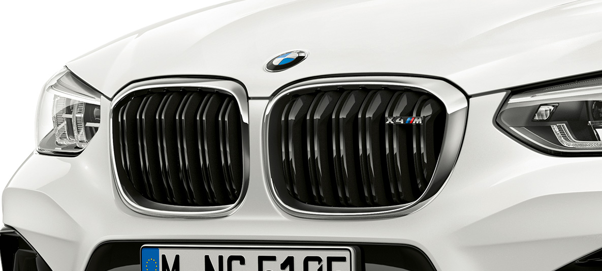 BMW X4 M, grelha M em forma de rim. BMW X4 M na pintura branco Alpine, exterior, dianteira, grelha M em forma de rim com realces em cromado e designação do modelo.