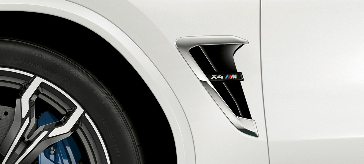 BMW X4 M, grelha lateral M. BMW X4 M na pintura branco Alpine, exterior, grelhas laterais M com realces em cromado e designação do modelo.