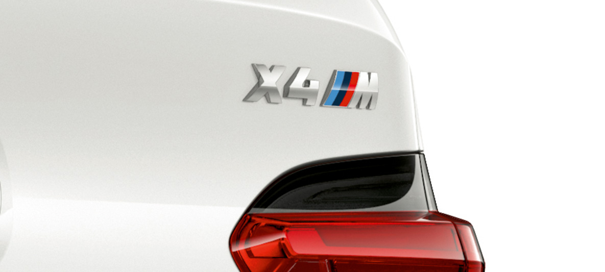 BMW X4 M, designação do modelo. BMW X4 M na pintura branco Alpine, exterior, grande plano da perspetiva traseira com designação do modelo.