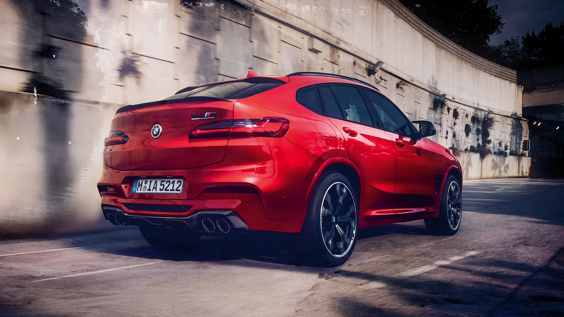 BMW X4 M Competition, perspetiva traseira lateral. BMW X4 M Competition na pintura vermelho Toronto metalizada, exterior, perspetiva traseira lateral.