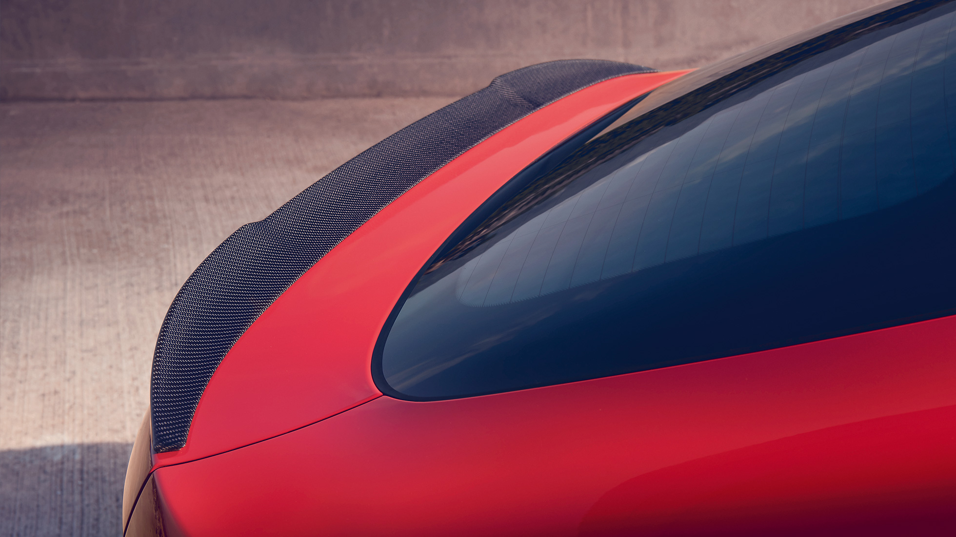 BMW X4 M Competition, spoiler traseiro M em carbono. BMW X4 M Competition na pintura vermelho Toronto metalizada, exterior, pack exterior M em carbono, perspetiva traseira detalhada com o spoiler traseiro M em carbono.