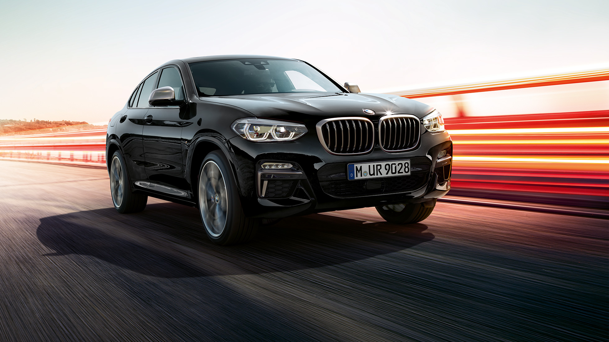 BMW X4 M40d, perspetiva frontal a três quartos. BMW X4 M40d na pintura preto Sapphire metalizada, exterior, perspetiva frontal a três quartos, lado esquerdo com faixas luminosas.