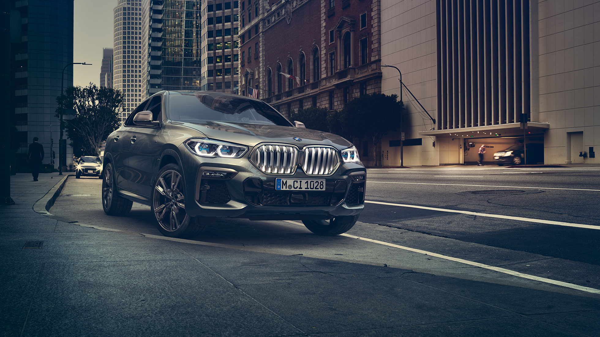 BMW X6 M50i parado BMW X6 M50i, perspetiva frontal a três quartos em frente a um cenário urbano