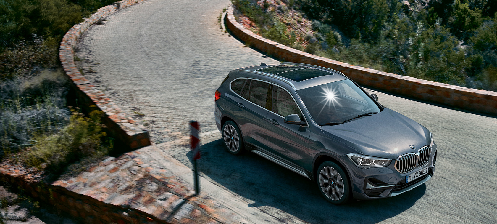 BMW X1, perspetiva frontal a três quartos. BMW X1, perspetiva frontal a três quartos, condução em frente a um cenário de montanha.