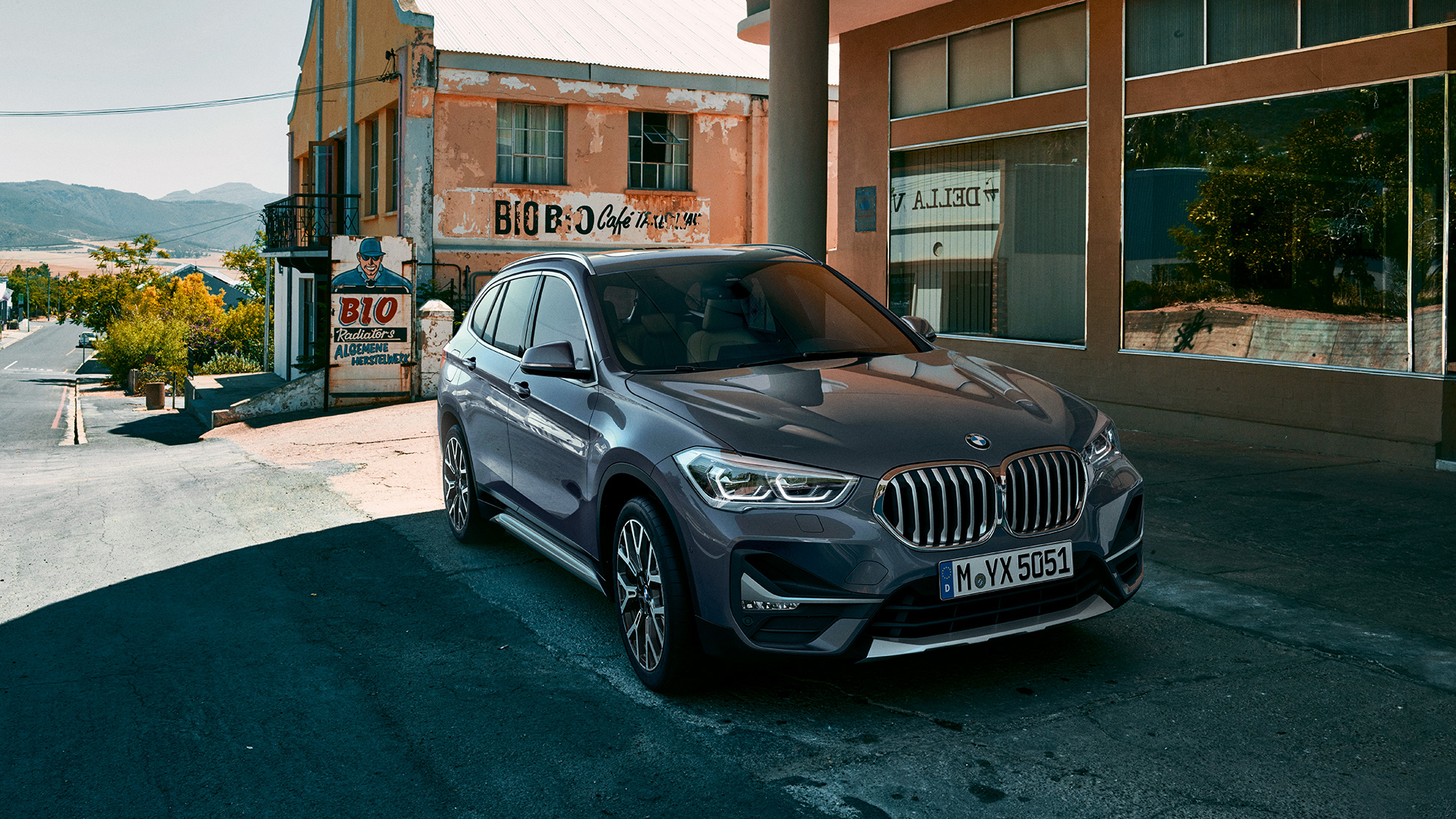 BMW X1, perspetiva frontal a três quartos. BMW X1, perspetiva frontal a três quartos, em frente a um cenário urbano.
