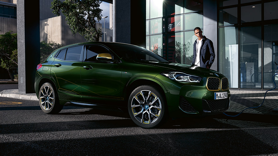 BMW X2, F39, pintura verde Sanremo metalizada, perspetiva lateral a três quartos com um modelo BMW X2, F39, pintura verde Sanremo metalizada, perspetiva lateral a três quartos com um modelo