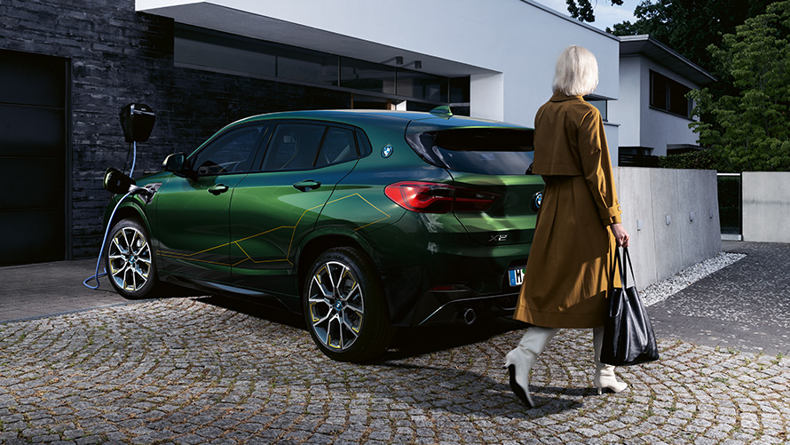 BMW X2, F39, pintura verde Sanremo metalizada, perspetiva traseira a três quartos com um modelo BMW X2, F39, pintura verde Sanremo metalizada, perspetiva traseira a três quartos com um modelo