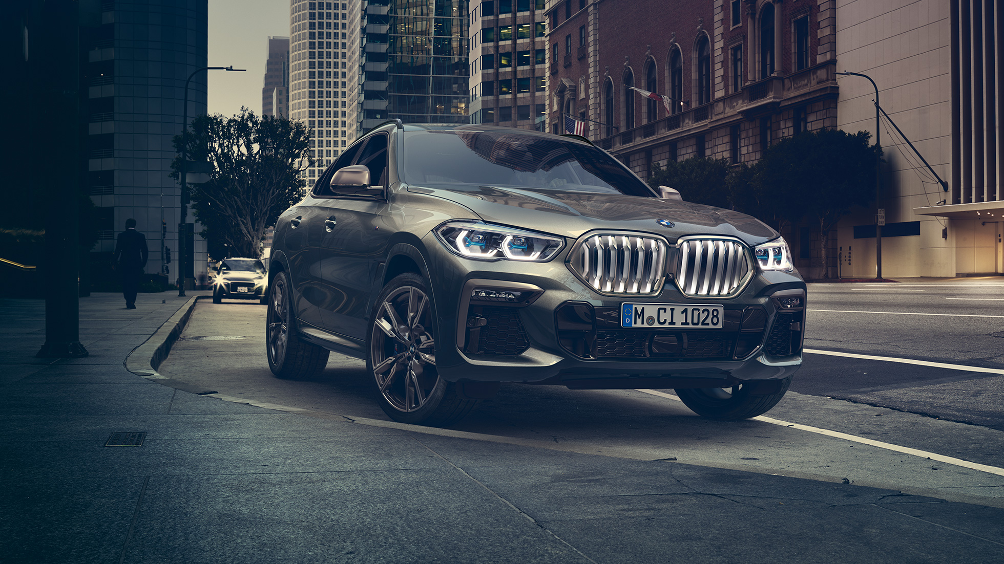 Suspensão adaptativa M Professional do BMW X6 Perspetiva dianteira a três quartos do BMW X6 em frente a um cenário urbano.