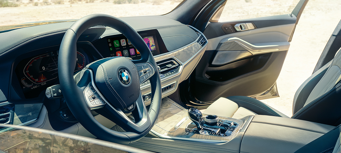 Interior do BMW X7 Interior do BMW X7: vista de fora para a primeira fila de bancos com vista para o volante, painel de instrumentos e bancos em pele
