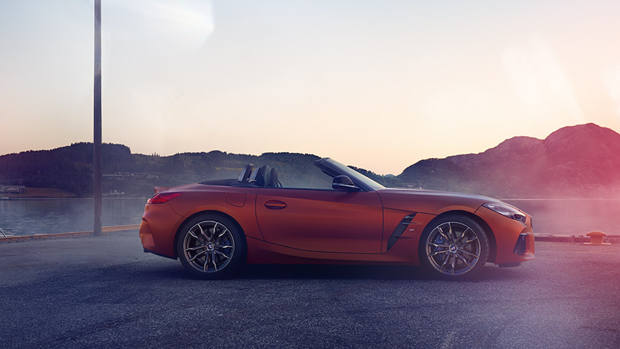 Perspetiva lateral do BMW Z4 First Edition em laranja Perspetiva lateral do BMW Z4 First Edition em laranja, numa paisagem de montanha