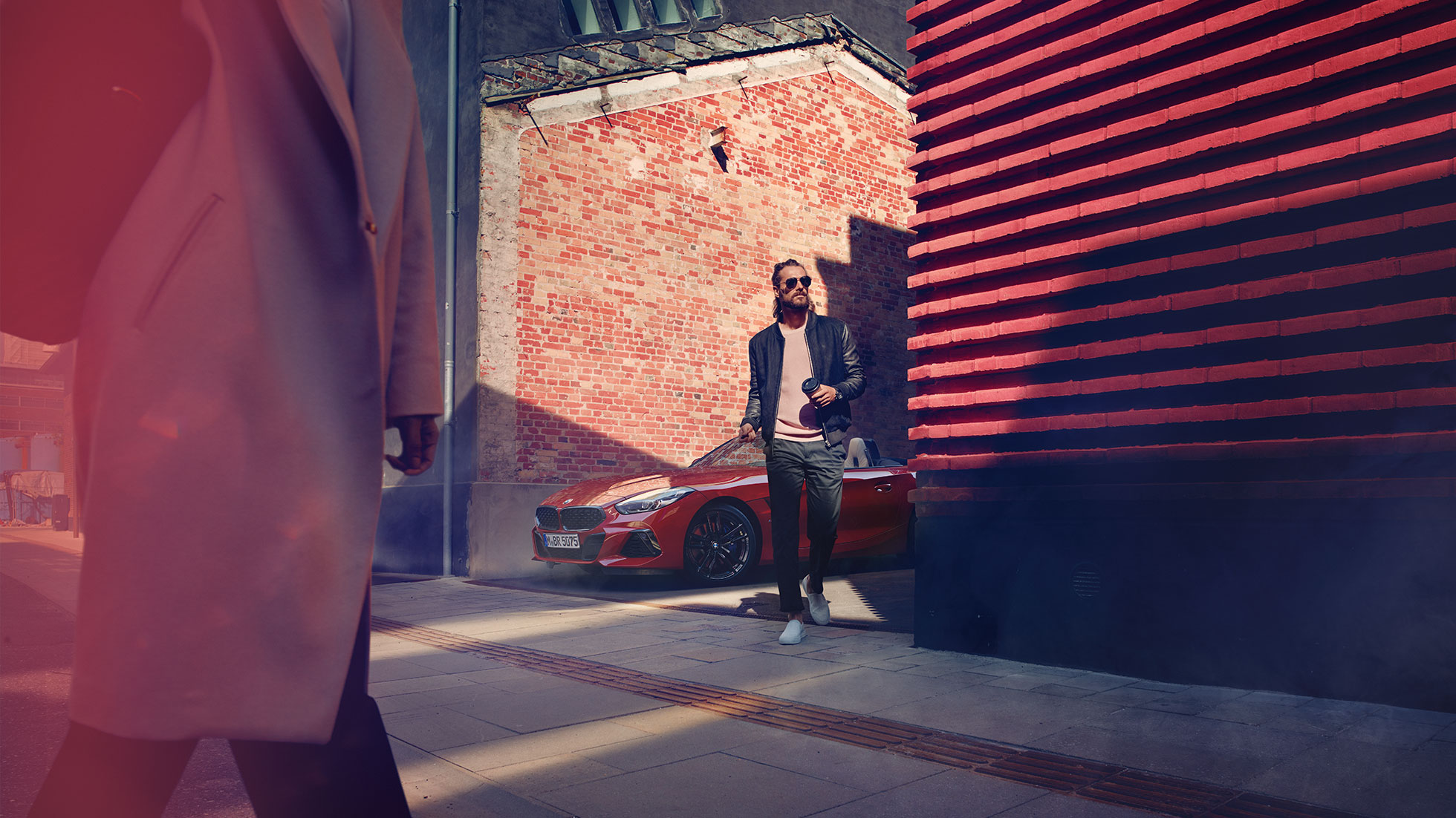 O BMW Z4 Roadster numa rua secundária Um homem numa rua secundária à frente do BMW Z4 Roadster