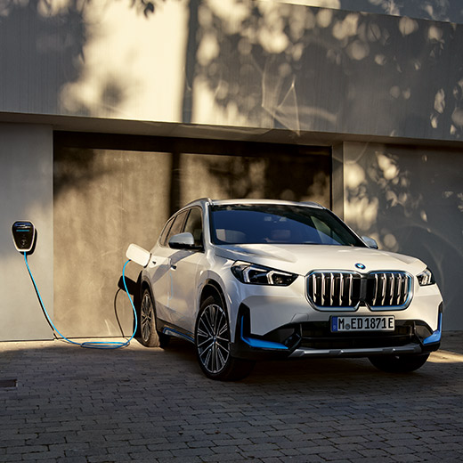 BMW iX1, U11, BEV, cenário de carregamento à frente de uma garagem