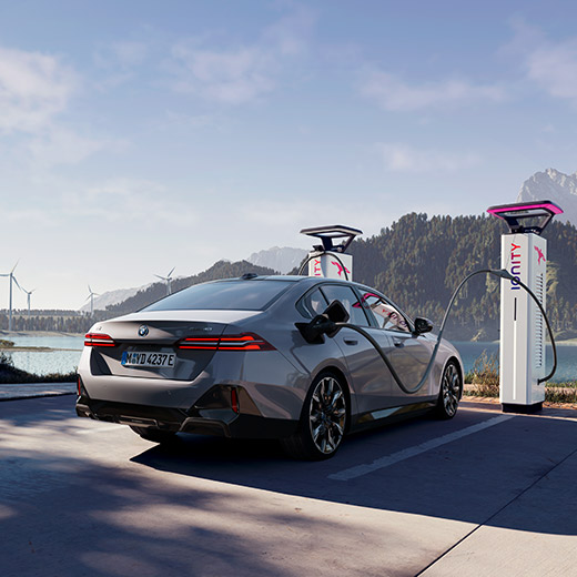 BMW i5 eDrive40, G60, num posto de carregamento à frente de um lago