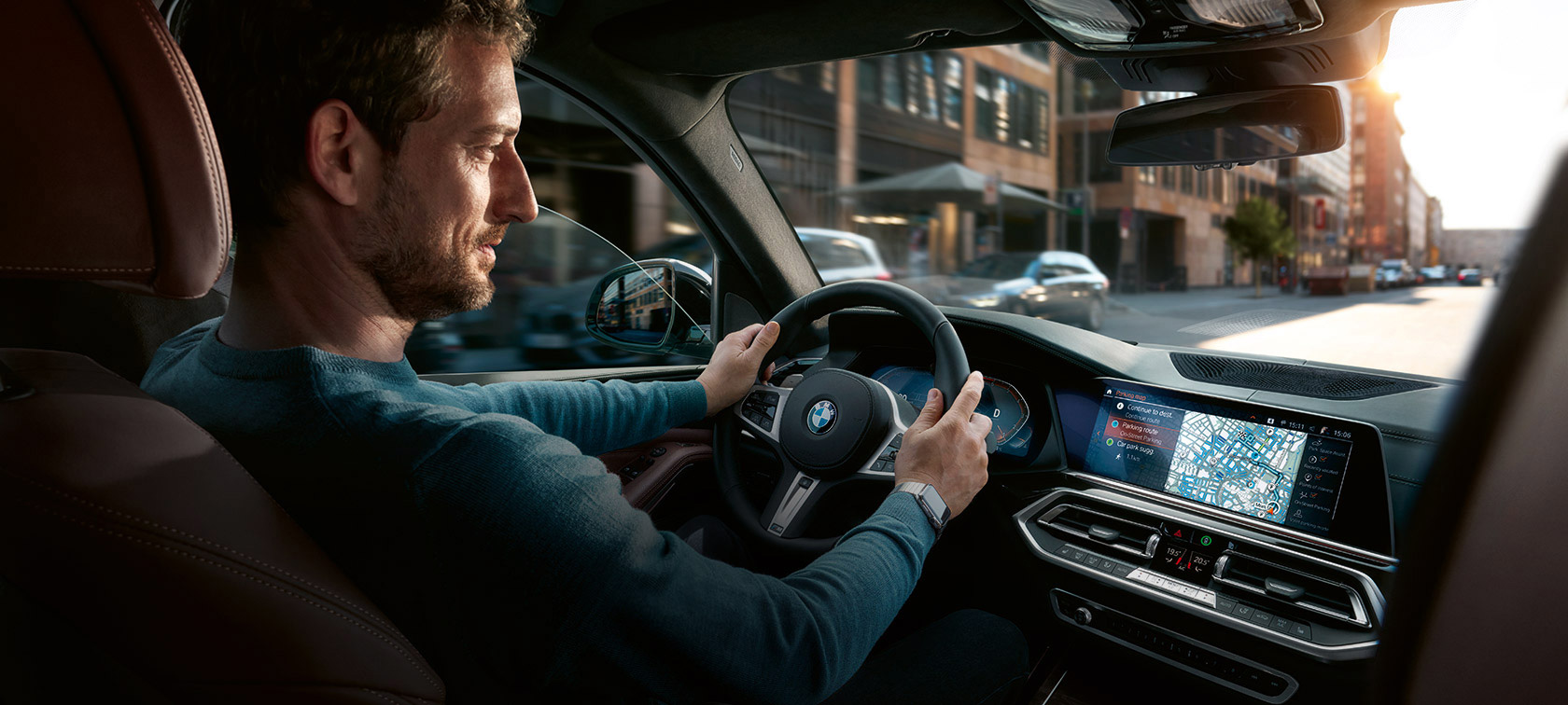 Navegação via BMW Maps Homem a conduzir um BMW com a navegação BMW Maps no ecrã de controlos.