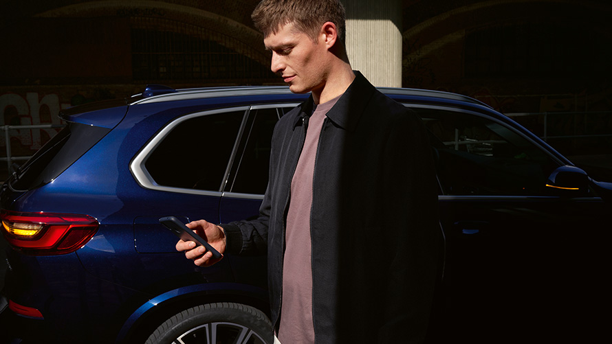 Chave digital BMW – instale até 5 utilizadores Chave digital BMW, instalar até 5 utilizadores, homem com smartphone em frente a um BMW X5