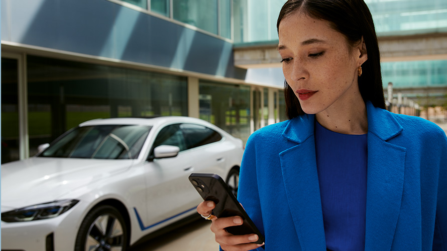 Mulher à frente de um BMW Mulher à frente de um BMW e a olhar para o seu smartphone