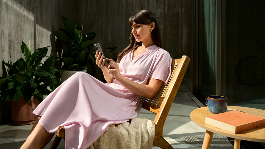 Mulher com vestido rosa com um smartphone na mão, Remote Inside View Remote Inside View, mulher com vestido rosa com um smartphone na mão numa cadeira