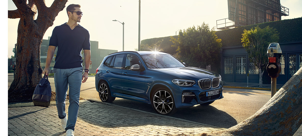 Homem com óculos de sol em frente a um BMW azul