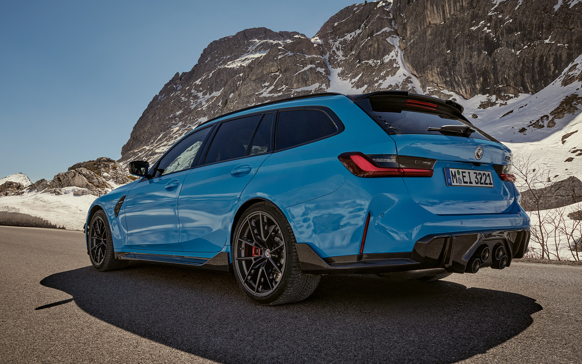BMW M3 Touring, G81, Acessórios BMW M Performance, perspetiva lateral a três quartos, em movimento BMW M3 Touring, G81, Acessórios BMW M Performance, perspetiva lateral a três quartos, em movimento em frente a uma paisagem de montanha