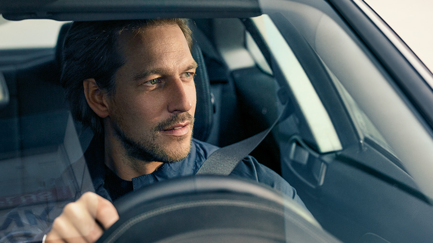 Um homem a conduzir um BMW e a olhar pelo para-brisas Um homem a conduzir um BMW e a olhar pelo para-brisas