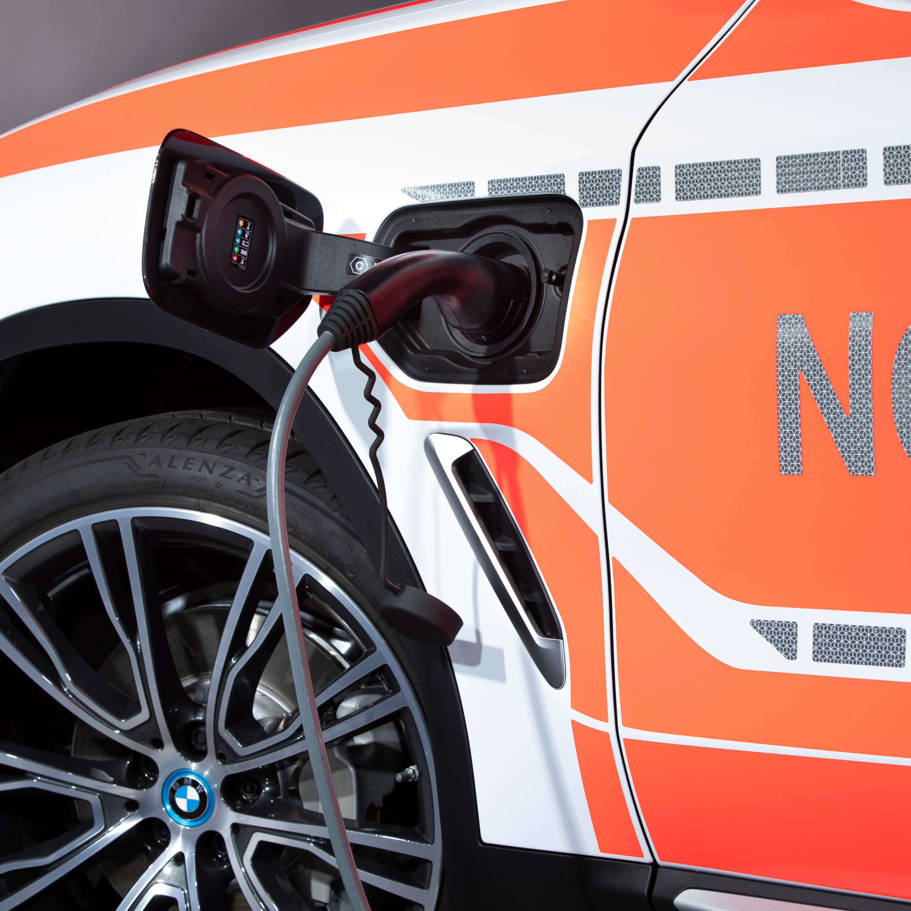 Um veículo das autoridades híbrido plug-in BMW a ser carregado; grande plano do cabo de carregamento