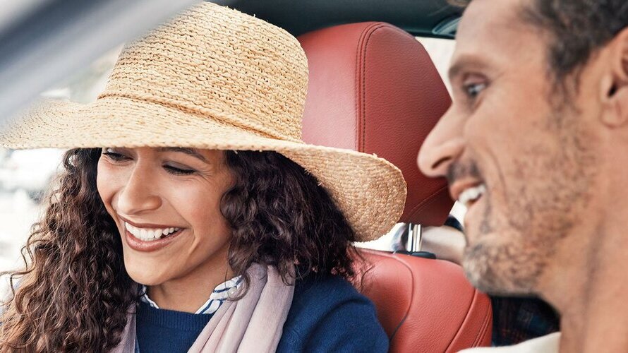 Duas pessoas sentadas num carro a sorrir.