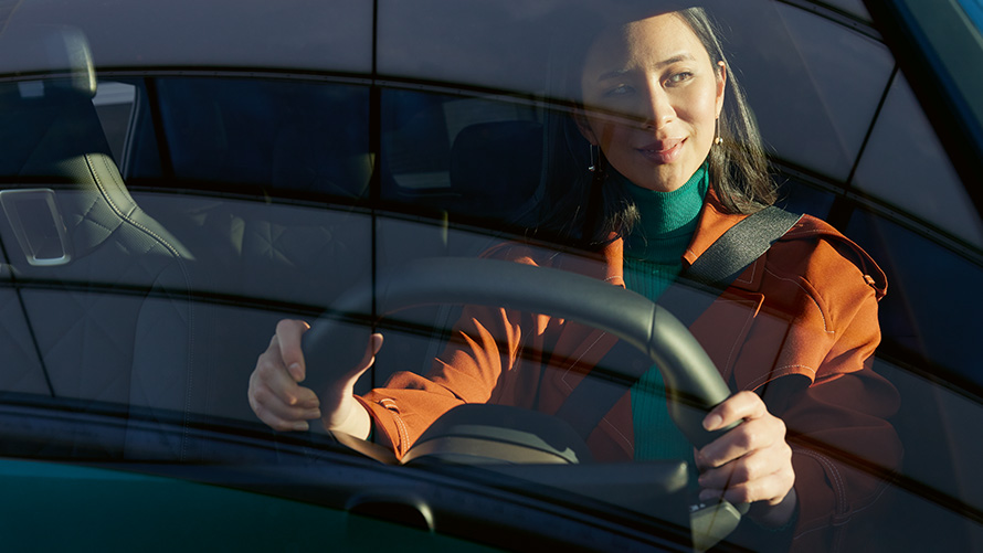 Mulher ao volante de um BMW Mulher com casaco laranja ao volante de um BMW