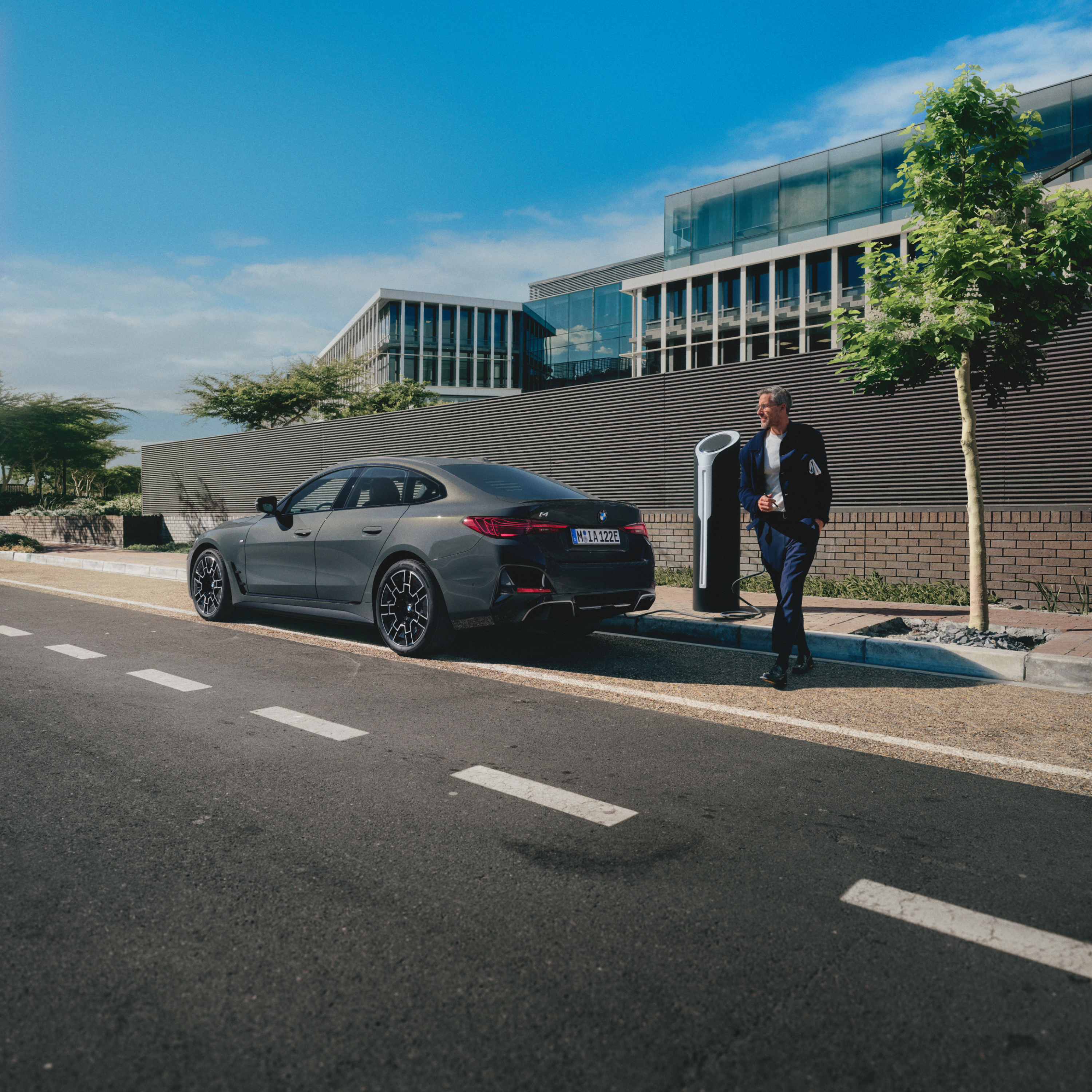 Pessoa de pé atrás de um BMW a carregar à beira da estrada