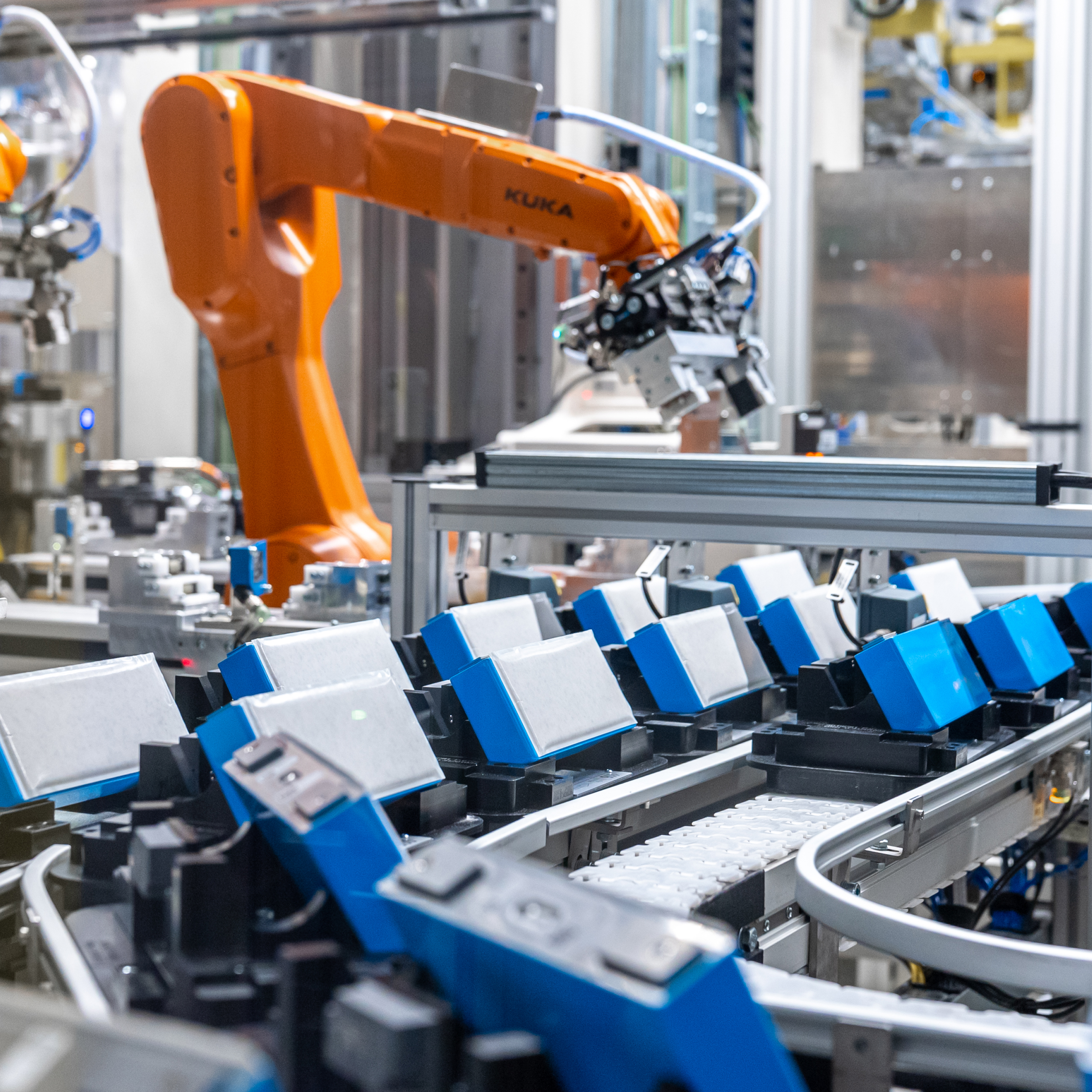 Grande plano de várias baterias azuis e brancas numa correia transportadora numa fábrica da BMW